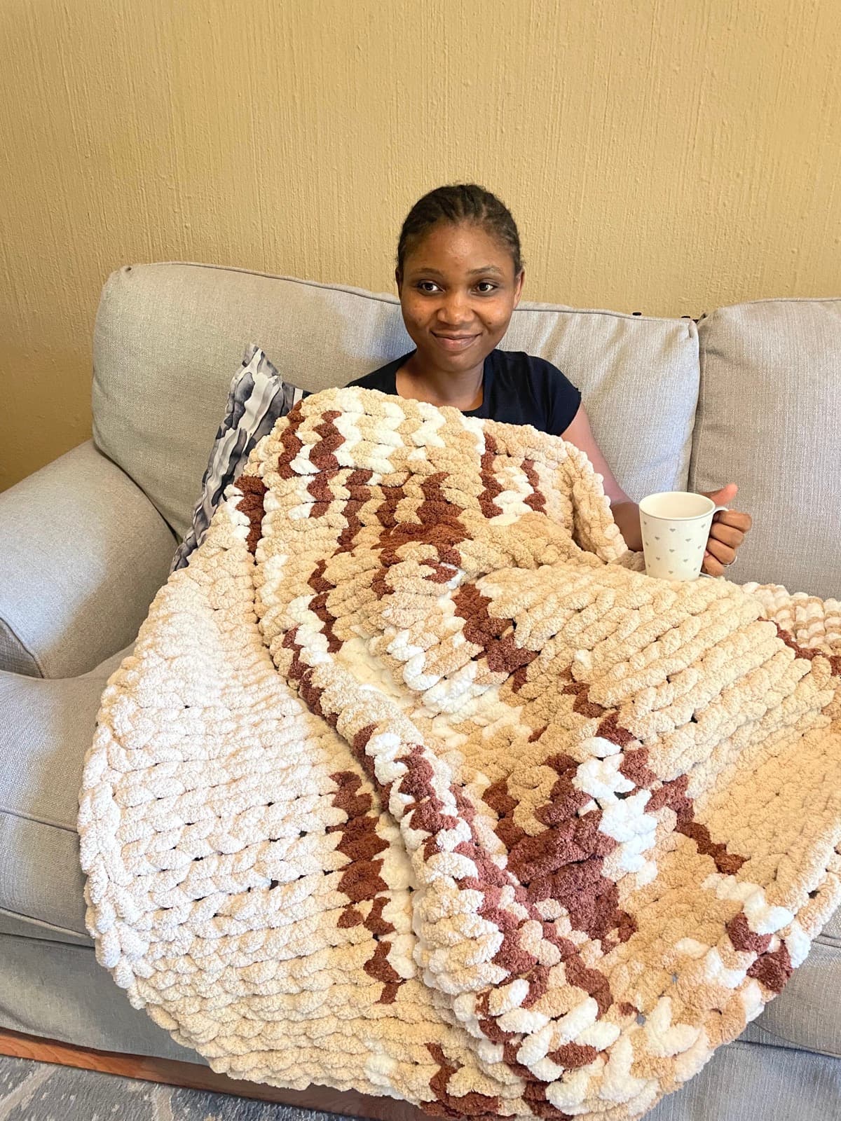 Melissa Ruvimbo Buchirai, founder of MelCrochet Gifted Hands, wrapped in a handmade crochet blanket